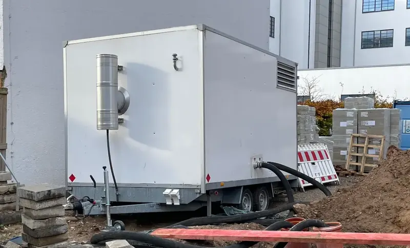 Chaufferie mobile sur remorque avec silencieux d’échappement à côté d’une maison sur un chantier