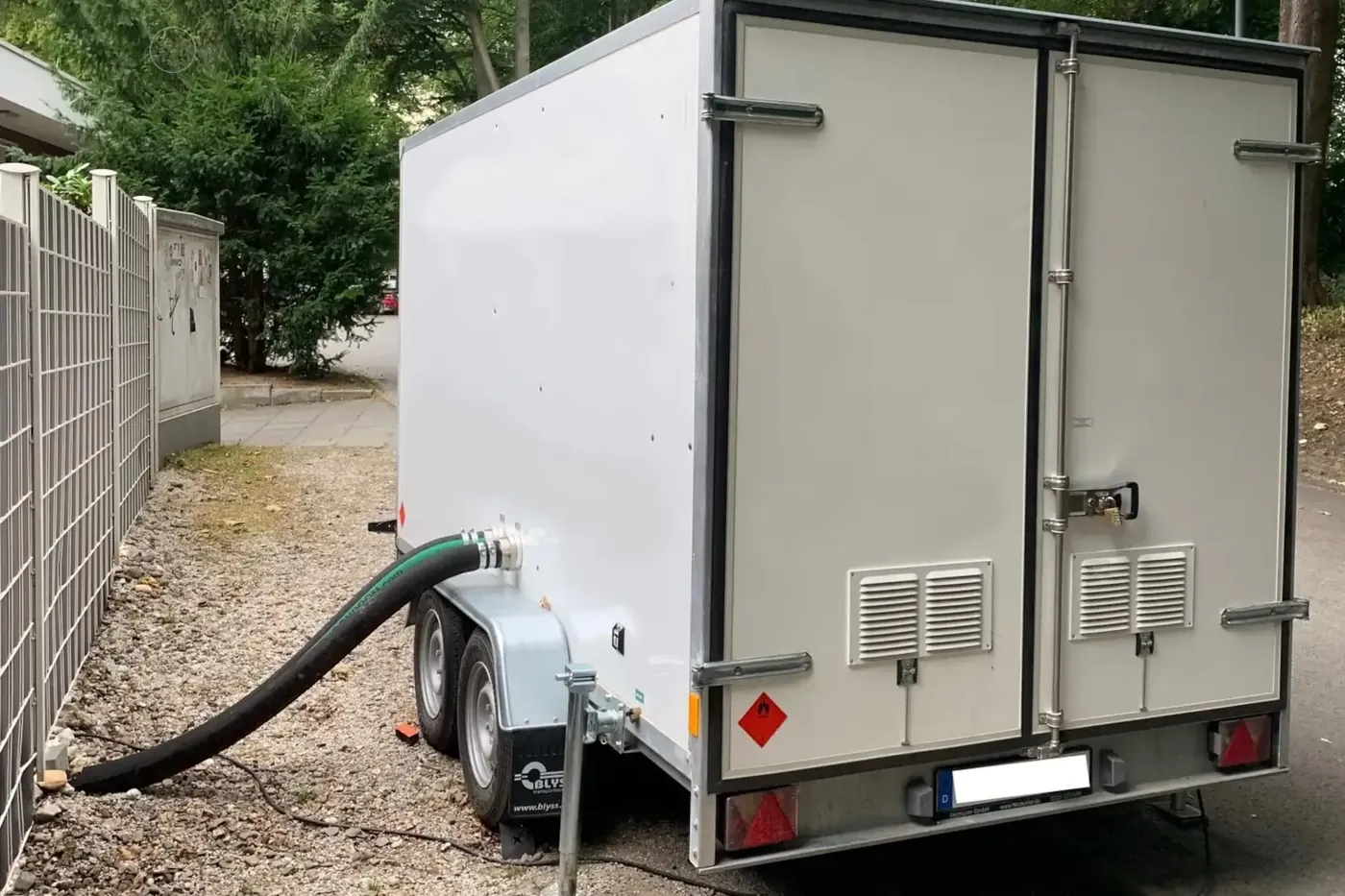 Chaufferie mobile dans une remorque fourgon devant un immeuble, les tuyaux de chauffage entrent dans le bâtiment