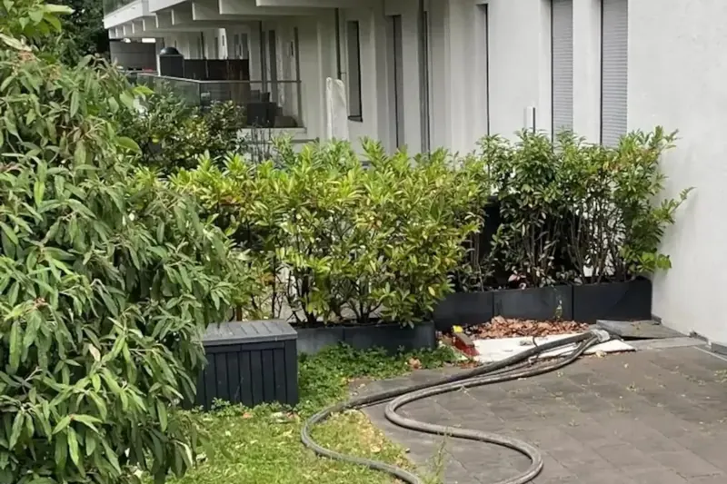 Isolierte Heizschläuche führen über die Terrasse in ein Mehrfamilienhaus